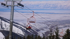 Picture of Karakol Ski-base. Chair lift and Issyk-Kul Lake. Chair lift of Karakol ski-base is one of many improvements of Karakol ski base. Dmitry and Anton Leshevy are in the chair lift on the background of trees and Issyk-Kul Lake.