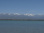 Lake Issyk-Kul. Karakol Peak and Oguz-Bashi Peak (Eltzin Peak). Photo of Issyk-Kul Lake. Kyrgyzstan. Peak Karakol (left, 5216m height) and Peak Oguz-Bashi (right, it was renamed to Eltzin Peak in 2002, height: 5168m).