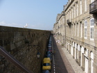 The old city is surrounded with fortress walls with people and gulls walking on them.
