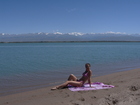 The day was wonderful, sights of the nature and landscapes were incredible. Me and Zhanna went along the shore of Issyk-Kul Lake to find a better photo views and took many pictures. At this photo: Zhanna, sand, Lake Issyk-Kul. At the background: Terskey Ala-Too range with main summits: Peak Karakol, Oquz-Bashi, Armstrong.